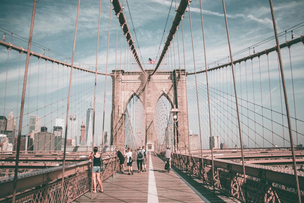 Pedestrians enjoy the view from Brooklyn Bridge on a summer day. Click on the picture for more info on our Offbeat New York bike tour to the very same place