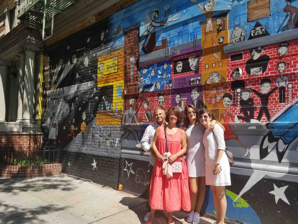 A family poing in front of mural in Harlem during an offbeat New York tour